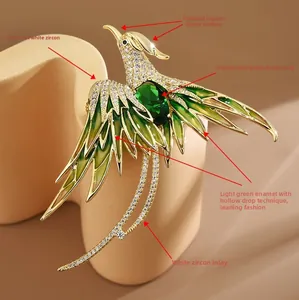 Dettaglio della spilla a fenice dorata con zircone verde e ali in smalto