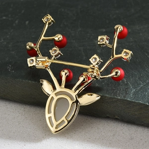 Broche cerf dorée élégante avec perles rouges et cristaux sur fond de roche sombre