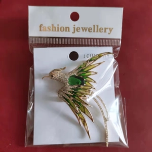 Detailed macro view of phoenix brooch with green enamel and sparkling white zircons