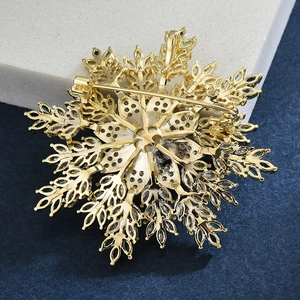 Detail view of the secure metal pin back on a gold snowflake brooch with blue crystals