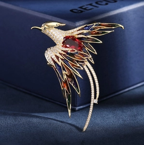 Close-up of a phoenix brooch with gold plating, multicolor enamel feathers and red gemstone