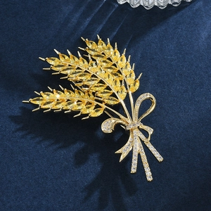 Macro shot of gold wheat brooch with amber zircons and pearls on navy blue velvet