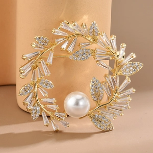 Vue macro d'une broche couronne plaquée or avec des oxydes de zirconium et une perle blanche