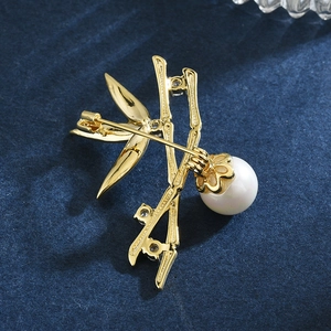 Elegante spilla in bambù dorato con perla e zirconi su tessuto blu scuro