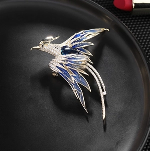 Detailed close-up of a phoenix brooch with blue enamel and sparkling white zircon crystals