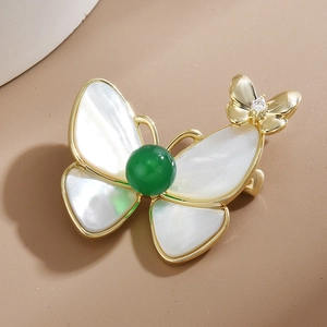 Élégante broche papillon avec ailes en nacre blanche et perle verte sur monture dorée