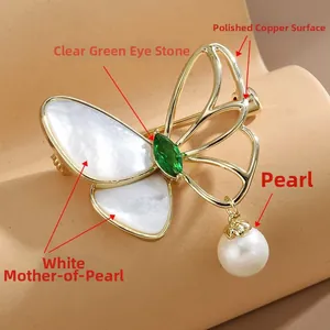 Detail of butterfly brooch with white shell wings, green gemstone, and pearl pendant