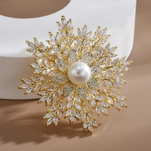 Elegant snowflake brooch with pearls and zircon crystals on a warm khaki background