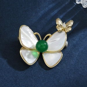 Exquise broche papillon avec ailes en nacre et perle verte sur fond en velours bleu