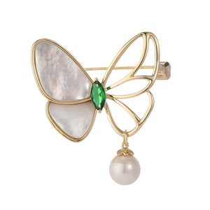 Golden butterfly brooch with white mother of pearl wings and green gemstone accent
