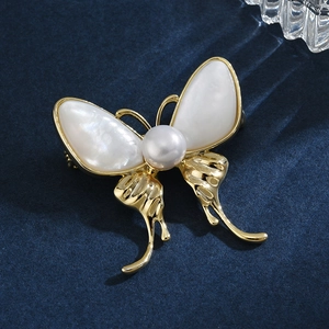 Broche papillon élégante avec des ailes en nacre blanche et une perle centrale raffinée