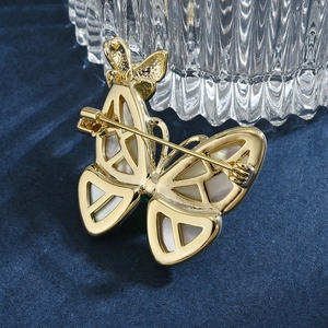 Exquise broche papillon avec ailes en nacre naturelle sur une base en métal doré chic