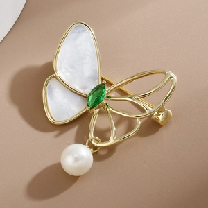 Elegant gold butterfly brooch with white shell wings, green gemstone and a pearl drop charm
