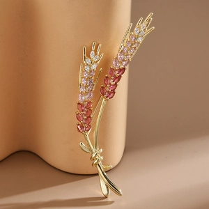 Détail de la broche épi de blé dorée avec des zircons dégradés roses et blancs