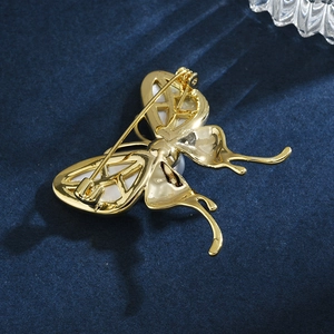 Élégante broche papillon en or avec nacre blanche sur fond de velours bleu luxueux