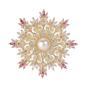 Elegant snowflake brooch with center pearl and pink gems on white background