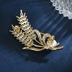 Elegant gold wheat brooch with a white pearl on premium deep blue velvet background