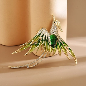 Elegant gold phoenix brooch with green gemstone and gradient enamel on beige pedestal