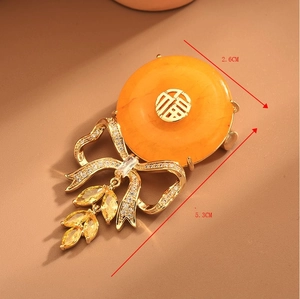 Detail of amber brooch with golden Fu character, zircon bow, and dimensions 5.3cm x 2.6cm