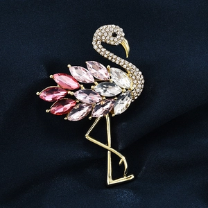 Broche flamant rose dorée avec cristaux roses sur un fond en soie bleu foncé