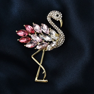 Broche flamant rose élégante avec cristaux sur fond de tissu en soie bleu foncé