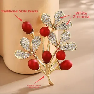 Détail macro d'une broche feuille avec perles rouges et zircons sur placage d'or cuivre