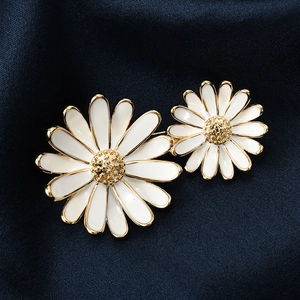Ensemble de broches marguerites en émail blanc et doré sur un fond élégant en satin bleu