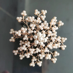 Détail macro de la broche perle en alliage avec base dorée et motif floral en étoile