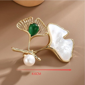 Détail macro de broche ginkgo de 4,6 cm avec gemme verte, nacre blanche et perle
