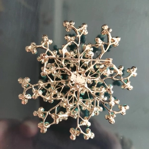 Détail macro du dos d'une broche branche dorée montrant le fermoir et la texture métal