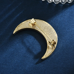 Elegant gold moon brooch with sea shell inlay shown from back on blue velvet