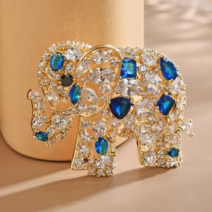 Élégante broche éléphant dorée avec zircons et accents bleus sur fond chaleureux