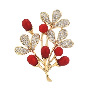 Broche élégante branche de baies dorées avec pierres rouges et cristaux blancs sur fond blanc