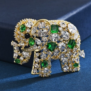 Élégante broche éléphant dorée avec oxydes de zirconium verts et blancs sur velours bleu
