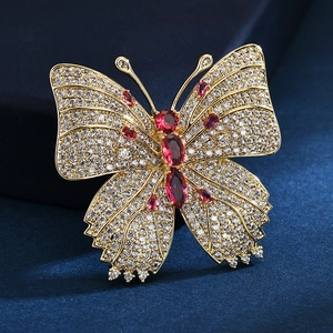 Élégante broche papillon en or avec pavé de zircons et pierres rouges sur velours bleu