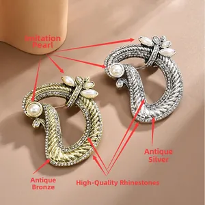 Close-up of vintage bronze and silver D-shaped brooch with pearls and rhinestones