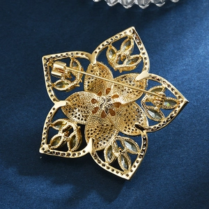 Elegante goldene Blumenbrosche mit gelben Steinen und Perlen auf dunkelblauem Stoff