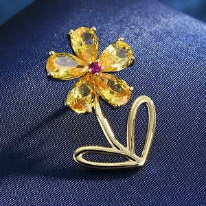 Macro shot of elegant floral brooch with yellow pear-cut crystals and gold metal petals