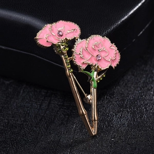 Detail of pink enamel carnation brooch with crystals on a textured black background
