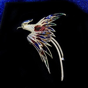 Détail de la broche phénix avec des ailes en cristal et pierre centrale rouge