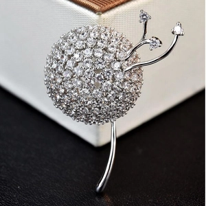 Macro shot of silver dandelion brooch with sparkling cubic zirconia on white jewelry box