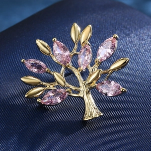 Detailed view of pink marquise gems and golden tree brooch on deep blue fabric