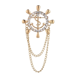 Macro detail of nautical wheel and anchor brooch with gold plating and rhinestones