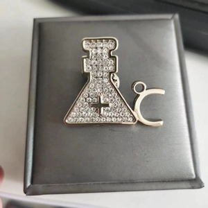 Sparkling crystal chemistry flask brooch with silver plating on grey jewelry box lid