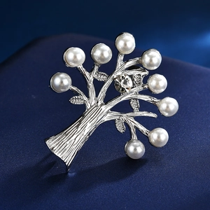 Vue macro d'une broche en forme d'arbre avec branches argentées et perles sur soie bleue