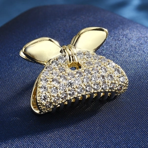 Macro detail of a golden bow hair claw clip with micro-pave white rhinestones