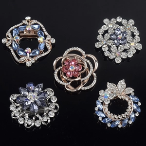 Macro detail of alloy flower brooches with colorful crystal inlays on black mirror