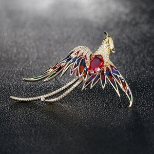Détail de l'élégante broche phénix avec pierre rouge et ailes en émail coloré sur fond noir