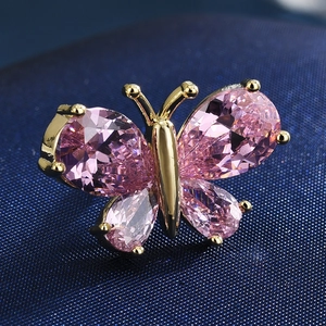Macro detail of a butterfly brooch featuring pink teardrop crystals and gold-plated metal