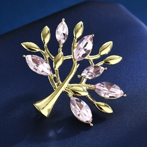 Broche arbre dorée avec cristaux marquise roses sur un fond bleu texturé chic
